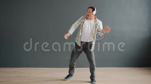 快乐成熟的亚洲男人戴着听音乐的耳机跳舞视频的预览图