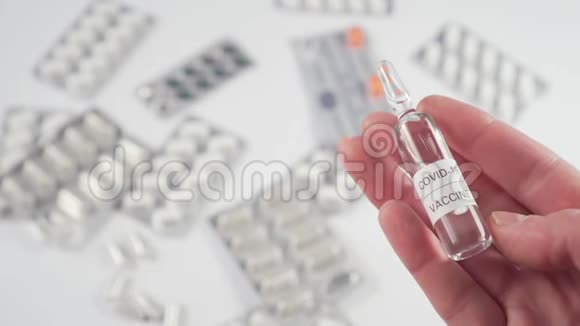 冠状病毒疫苗安瓿在白色桌子上的药丸和胶囊的背景上视频的预览图