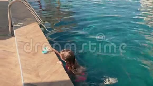 青少年女孩在度假酒店的室外游泳池游泳小女孩漂浮在蓝色的游泳池里游客视频的预览图