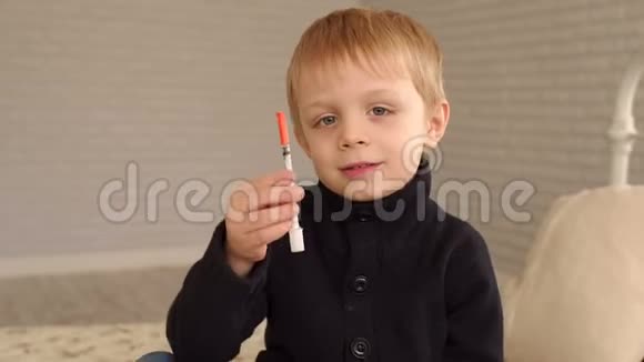 一个小男孩坐在家里的床上拿着一个胰岛素注射器视频的预览图