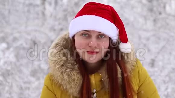 穿着冬暖夏凉的衣服戴着圣诞帽的年轻女孩在森林里跳舞看着镜头背景视频的预览图