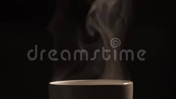倒入白杯的热茶或咖啡对黑底有白烟和蒸汽的影响视频的预览图
