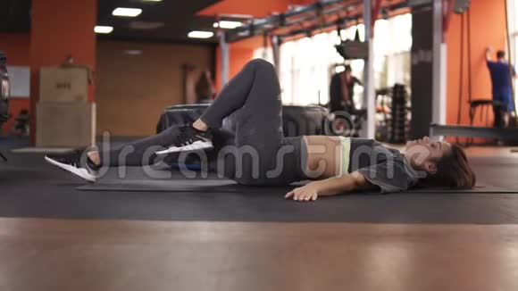 侧视一个躺在背部的女人进行运动扭转身体的灵活性女性的特写视频的预览图