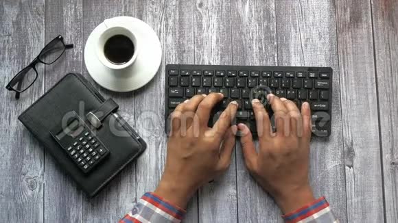 办公室桌上键盘上的人手打字的俯视图视频的预览图