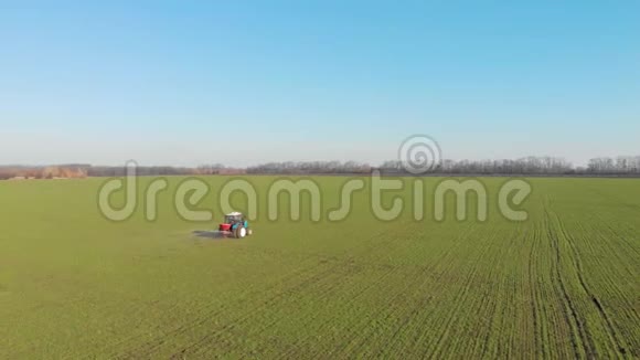 拖拉机在绿色的大田里施肥的鸟瞰图视频的预览图