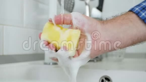 男人手里拿着用清洁剂和大量泡沫浸泡的洗碗海绵视频的预览图