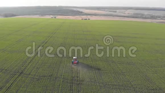 在绿色的大田里拖拉机给化学物质施肥的鸟瞰图视频的预览图