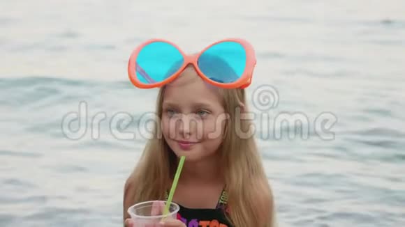从海边的塑料杯喝鸡尾酒的快乐女孩视频的预览图