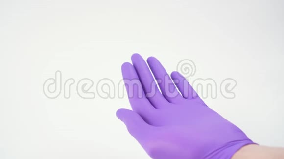 使用消毒喷雾剂在白色背景的蓝色外科防护手套中卫生处理手部视频的预览图