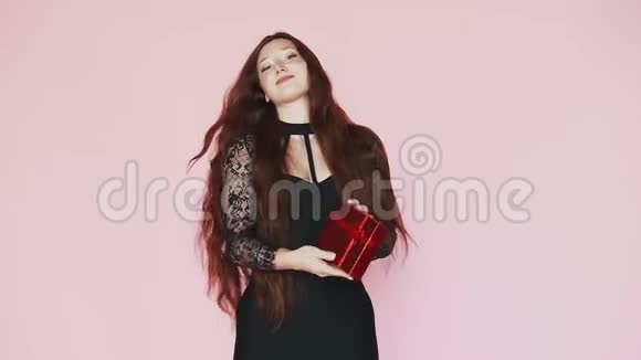 红发美女向镜头展示礼盒慢动作在粉色背景上视频的预览图