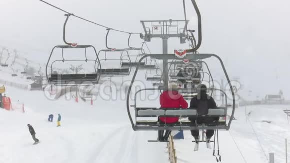 一对夫妇骑着滑雪缆车在下雪时爬到山顶滑雪视频的预览图