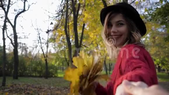 快乐的女性在秋天的公园里奔跑在夕阳的温暖阳光下秋天的季节带着一束黄叶视频的预览图