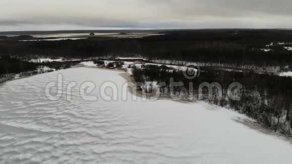 冬天在森林里冰冻的湖泊和河流下飞行视频的预览图