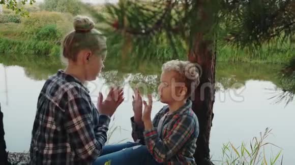 小女孩和男孩在针叶林的河岸上玩馅饼蛋糕快乐的姐姐和哥哥玩拍子视频的预览图