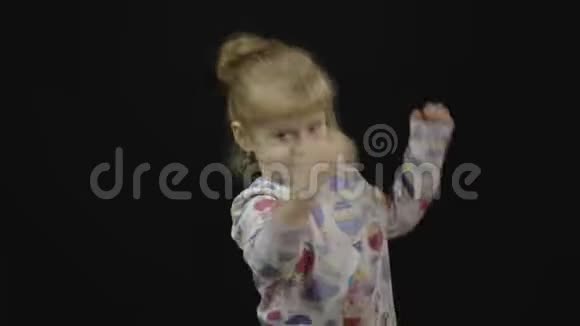 睡衣里的小女孩在黑色背景下跳舞和玩耍幸福快乐视频的预览图