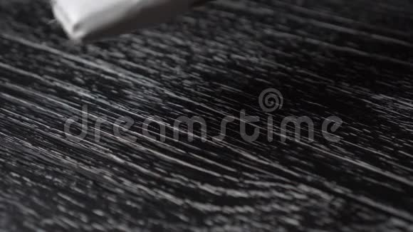 刷子在黑色的旧木表面上涂抹白色油漆视频的预览图