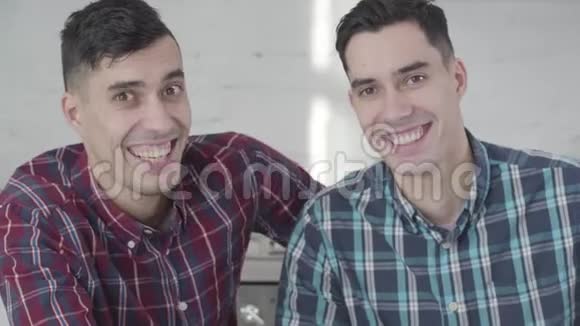 特写白种人双胞胎兄弟的肖像看着相机微笑两个积极的年轻人在家摆姿势视频的预览图