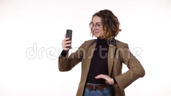 一位迷人的时尚年轻女子卷曲的短发通过电话进行视频聊天站着谈笑风生视频的预览图