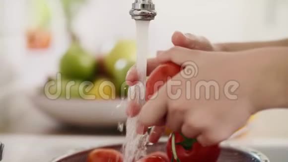 人类的手洗新鲜的西红柿视频的预览图