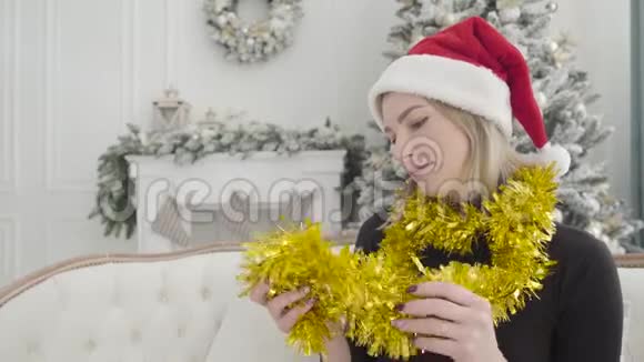 戴着新年帽子的可爱白种人女孩坐在装饰圣诞树的背景下两个孪生兄弟站在那里视频的预览图