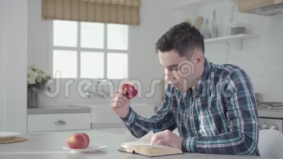 白人男子一边看书一边吃苹果一边推着他的背坐在旁边视频的预览图