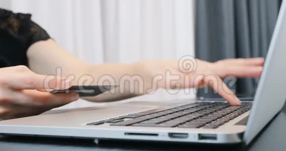 女士手在笔记本电脑上输入银行卡号女人花钱买网上购物金融和货币支付概念视频的预览图