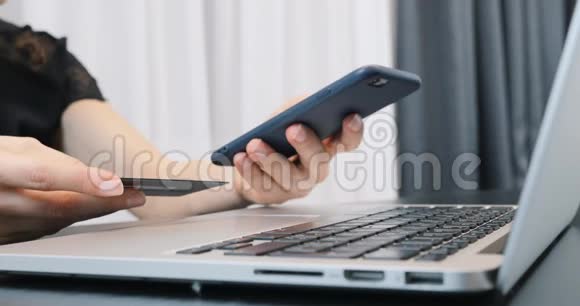 手里拿着智能手机和银行卡的女人关门女手指在电话中输入银行卡号网上付款视频的预览图