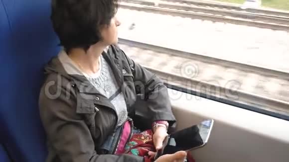 白人妇女坐在靠窗的火车上手里拿着一块平板电脑视频的预览图
