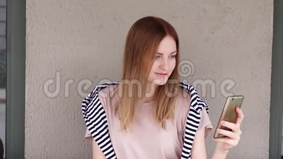 金发女孩坐在咖啡馆里在智能手机上自拍视频的预览图