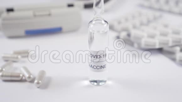 冠状病毒疫苗一只手戴着防护手套从一张白色桌子上拿起一支安瓿上面有医疗设备和帽子视频的预览图