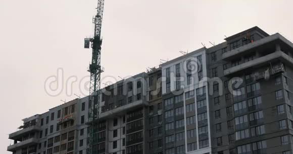 建筑工地大型施工吊车工程起重机在施工现场顶着灰色多云的天空工作建造高层建筑视频的预览图