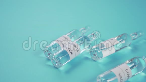 冠状病毒疫苗和COVID19一只手戴着防护手套在蓝色的桌子上放了一个带药的安瓿视频的预览图