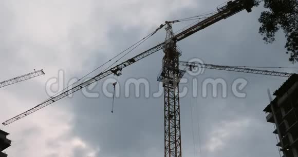 高吊车在建筑工地上工作与灰色的天空与云吊车施工现场视频的预览图