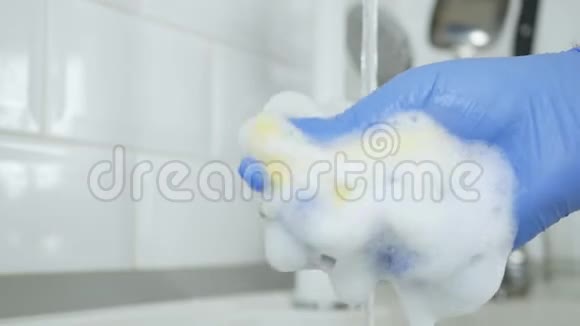 手与橡胶手套使用洗碗机海绵充满泡沫和洗涤剂视频的预览图