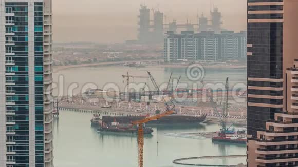 鸟瞰迪拜码头摩天大楼与建筑工地和棕榈朱梅拉岛背景时间推移视频的预览图