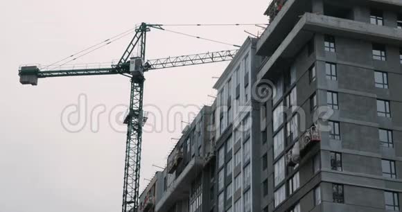 建筑工地高吊车施工封闭摩天大楼的施工过程中起重机和工人正在建造房屋高丽视频的预览图