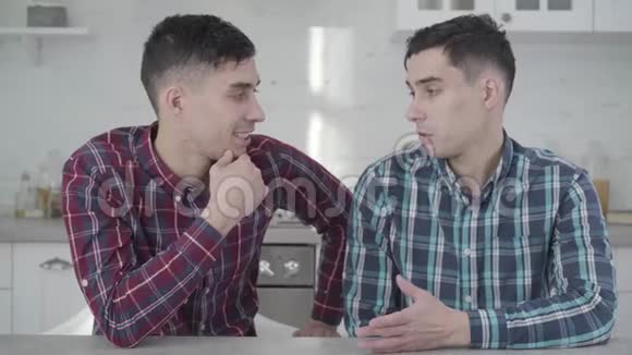 特写两个成年白种人双胞胎兄弟互相交谈转向相机和微笑积极的青年视频的预览图