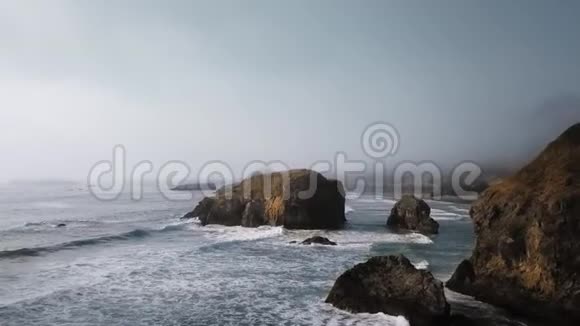 空中拍摄的波浪和巨大的突出石头在雾中视频的预览图
