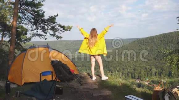 穿黄色雨衣的年轻游客站在山顶视频的预览图