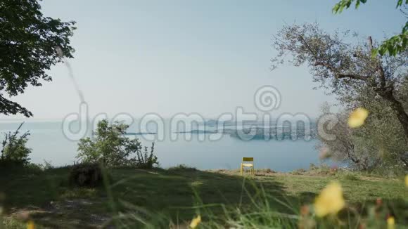 在俯瞰意大利最大湖泊加德纳湖山坡上一张孤独的黄色椅子视频的预览图