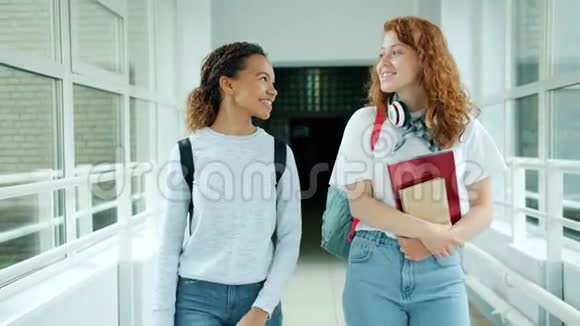 快乐的女生们拿着书在大学大厅里谈笑风生视频的预览图