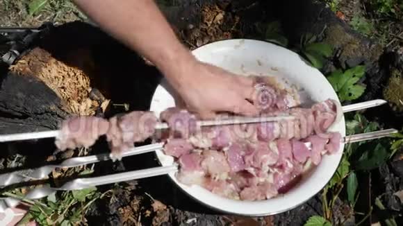 人把生肉粘在扦子上在烤架上准备肉户外烧烤炒肉烹饪工艺视频的预览图