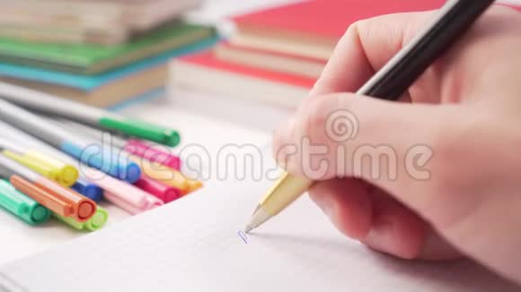 金色的黑色钢笔在白色桌子上的笔记本上写字上面有书和多色的记号笔视频的预览图