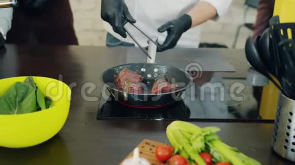 熟练的男厨师在煎锅里煮肉和一群人一起工作视频的预览图