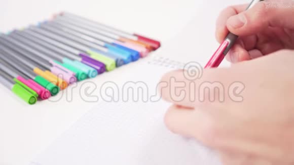 白色桌子上的多色钢笔手准备一个红色视频的预览图