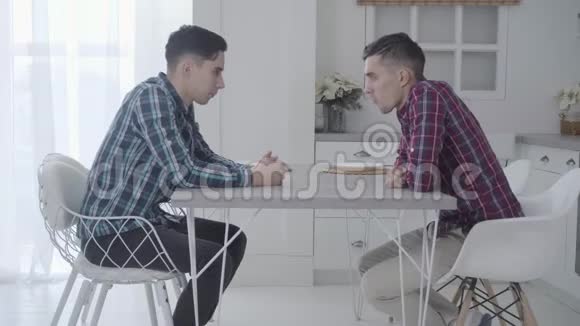 两个成年白种人双胞胎兄弟坐在桌子前交谈友好的兄弟姐妹视频的预览图