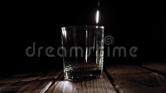 特写的威士忌倒在一个黑色背景的玻璃杯里动作缓慢视频的预览图