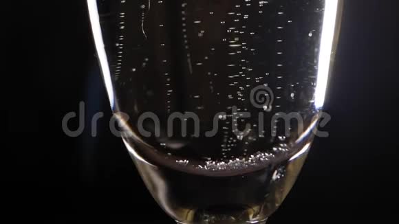 一杯香槟酒的特写镜头黑色背景上有气泡动作缓慢视频的预览图
