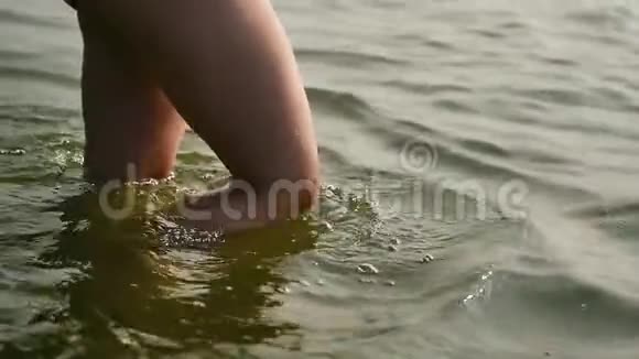女孩的脚和腿在水波上行走苗条的女性腿在海边的水波上行走假日在海滩上缓慢地视频的预览图