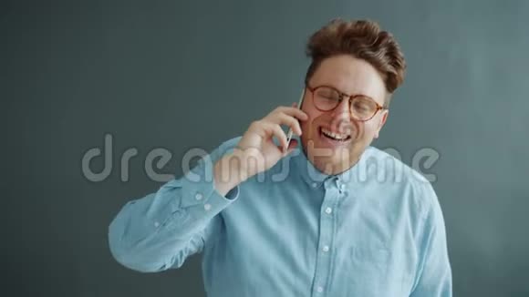 玩手机的家伙笑着享受灰色背景下的交流视频的预览图